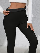 Close-up of embroidered logo detail on Royale Reflect Elevé Black Leggings waistband.