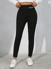 Model wearing Royale Reflect Elevé Black Leggings, front view showcasing embroidered waist detail.