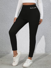 Model stretching in studio wearing Royale Reflect Elevé Black Leggings and sports bra.