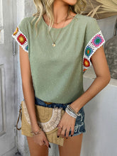 Model side profile showcasing  geometric crochet sleeve trim detail styled with bootcut jeans and accessories for a complete look, in sage.