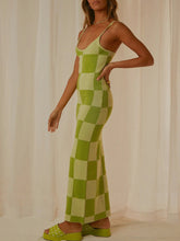 Side view of a model in Sage Luxnometry Maxi Sweater Dress showcasing its chic two-tone angular design and effortless fit in a mansion corridor.