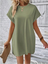 Model posing in Sage Rahluna Mini Tee Dress with gold hoops and platform sneakers at a downtown café.