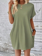 Model front view showcasing the soft round neckline, cuffed short sleeves, and side pocket detail of the Sage Rahluna Mini Tee Dress styled with hoop earrings and platform sneakers.