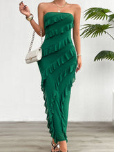 Model in the Dark Green Seraflore™ Maxi Dress standing by a tropical plant in a luxe garden patio setting.
