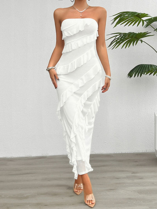 Model posing in the White Seraflore™ Maxi Dress by a tropical plant in a luxe beach resort courtyard.