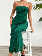 Model in the Dark Green Seraflore™ Ruffled Slit Back Tube Maxi Dress seated on a bar stool, paired with metallic heels and emerald stud earrings in a chic outdoor bar setting.