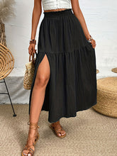 Seravellea Black frill midi skirt front view styled with white top, straw handbag, and brown sandals at a restuarant.