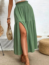 Seravellea Matcha green frill midi skirt front view styled with white top, straw handbag, and brown sandals at a photo studio.