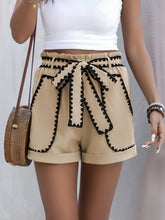 Close-up of Seravelya Wave Shorts styled with crossbody bag highlighting contrast trim and waist tie in tan