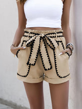 Close-up of model’s hands in both pockets of Seravelya Wave Shorts tan with wavy trim detail