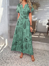 Model in gum leaf Serenoor jumpsuit, styled with tan woven clutch and jewelry, enjoying a serene morning coffee at a beach house balcony.