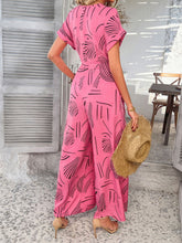 Model back view in hot pink Serenoor jumpsuit, paired with a straw hat and accessories at a beach house.