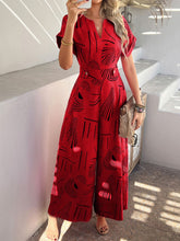 Scarlet Serenoor jumpsuit styled with open-toe heels, worn by model at a lively oceanside art gallery reception.