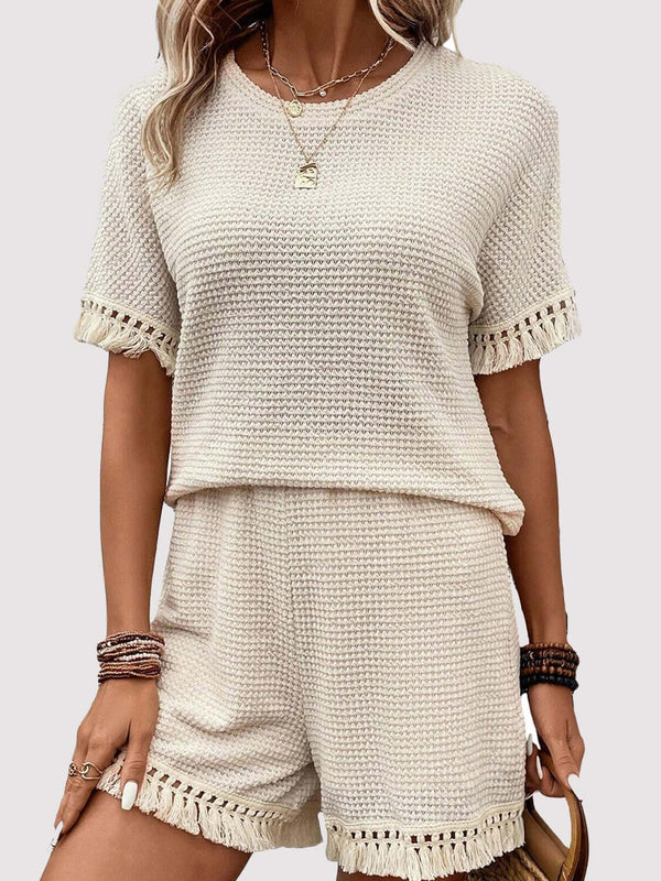 Model wearing the cream Shakaluxe Tassel Shorts Set styled with jewelry, a brown handbag, and sandals ready for a boardwalk beach adventure. 