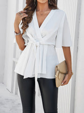 Side profile of model wearing the white tied front peplum blouse, highlighting the flattering waist-cinching tie and feminine silhouette.