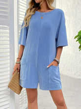 Model styled in sky blue Breezy Bold Romper paired with strappy platform sandals exploring activity options at a resort.