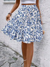 Sky blue Florévyn Floral Print Midi Skirt walking view styled with white tube top, highlighting frill tiers and ruffled hem