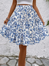 Model posing in sky blue Florévyn Floral Print Midi Skirt featuring frill tiers and ruffled hem