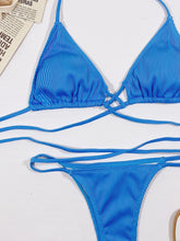 Close-up flat lay of sky blue halter neck crisscross ribbed bikini set highlighting ribbed fabric texture and long adjustable straps