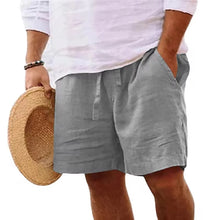 Person wearing gray Solivaro Shorts and a white shirt, holding a straw hat.