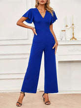 Model in Navy Soralia DrapeSuit, styled for a daytime brunch or garden party, showcasing flutter sleeves and elegant V-neckline.