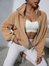 tan turtleneck zip up jacket stretching pose