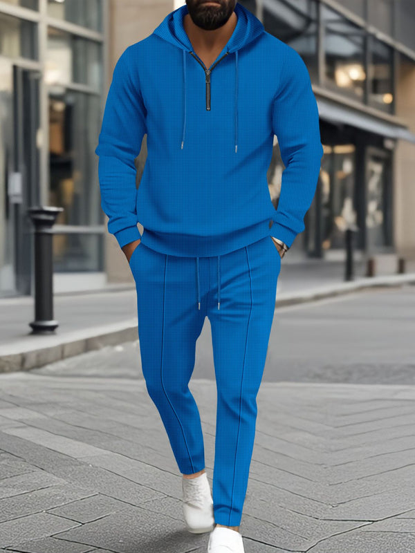 Model front view shopping in Minneapolis wearing the Blue Tavvion TerrainFlex Waffle-Knit Half Zipper Hoodie and Pants Set  paired with white sneakers.