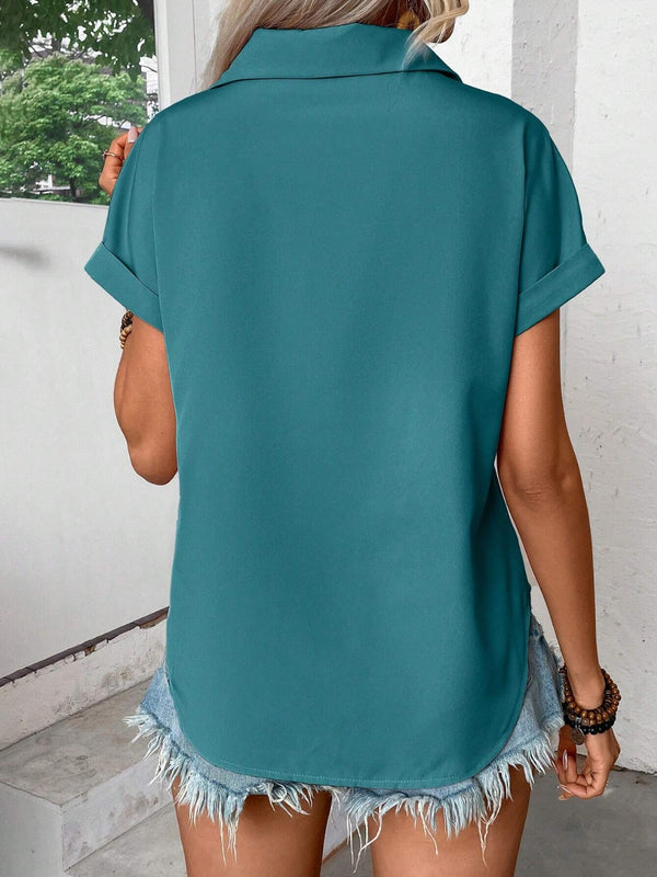 Back view of model showcasing the lightweight, relaxed fit of the teal pleated collared neck short sleeve blouse, paired with white trousers.
