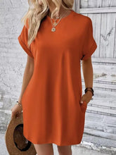 Woman strolling through a farmer’s market in Terracotta Rahluna Mini Tee Dress with a straw hat and layered necklaces.