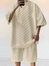 Front view of man taking a selfie photo wearing khaki Therion Boldline Set with round neck checkered shirt and shorts, styled with sneakers and accessories.