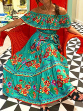 Turquoise Isadorae Maxi Dress styled with white sandals and beach tote, model seated in big red  chair.
