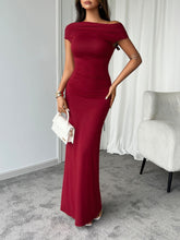 Model strolling in burgundy Vareliya Maxi Dress along a nighttime cityscape with accessories.