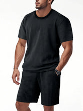 Men's black textured top and shorts set, close-up with hand in pocket