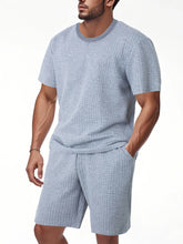 Men's light gray textured top and shorts set, close-up with hand in pocket