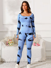 Model in light blue Prism Flow jumpsuit, front view highlighting scoop neck and tie-dye print.