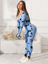 Woman in light blue Prism Flow jumpsuit lifting weights, side view.
