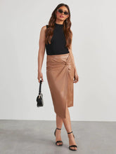 Full body cross leg pose in tan Velvanyx Twist Skirt showcasing side slit and twisted knot detail