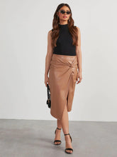 Tan Velvanyx Twist Skirt styled with black mock neck bodysuit, sunglasses, earrings, black handbag, and black slingback ankle strap heels