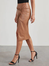 Side walking pose wearing Velvanyx Twist Skirt tan with side slit and twisted knot detail