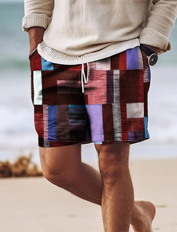 Man walking on beach wearing burgundy geometric color block shorts.