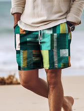 Man walking on beach wearing green geometric color block shorts.