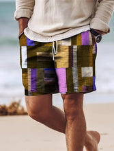 Man walking on beach wearing pink-purple geometric color block shorts.