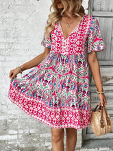 Vesaluna Paisley Print Tie Neck Dress in pink worn by model strolling through a local weekend market with a woven bag.