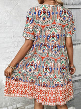 Back view of Vesaluna Paisley Print Tie Neck Dress in sherbet, showcasing short sleeves and flattering A-line silhouette.