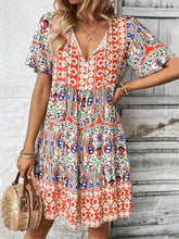 Model wearing Vesaluna Paisley Print Tie Neck Dress in sherbet, styled with a straw hat and nude heels for a chic daytime look.