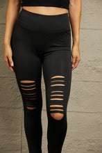 Close-up of distressed detailing on black leggings, showing bold rip texture and fabric quality.