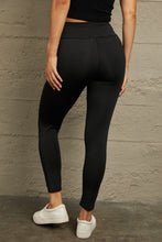 Rear full-length view of black distressed leggings, showcasing wide waistband and seamless back design.