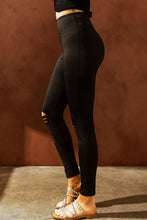Side profile of model wearing distressed black leggings, highlighting curve-hugging fit and thigh distressing.