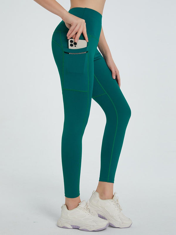 side view showing stretch fabric of virexaform sculpt leggings dark green with phone in side pocket