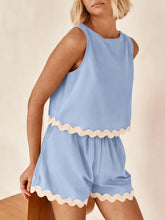 Model wearing the Pastel Blue wavy mirage contrast trim short set sitting in a beach chair.